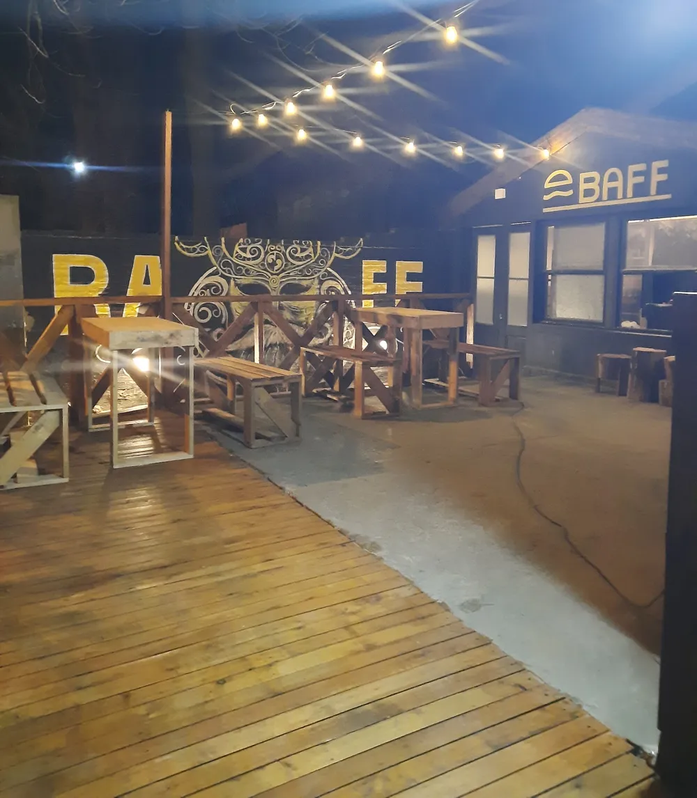 Patio de BAFF con deck de madera, mesas y luces colgantes